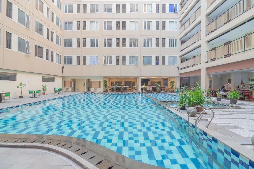 a swimming pool in front of a building at RedDoorz Apartment @ Emerald Towers Bandung in Bandung