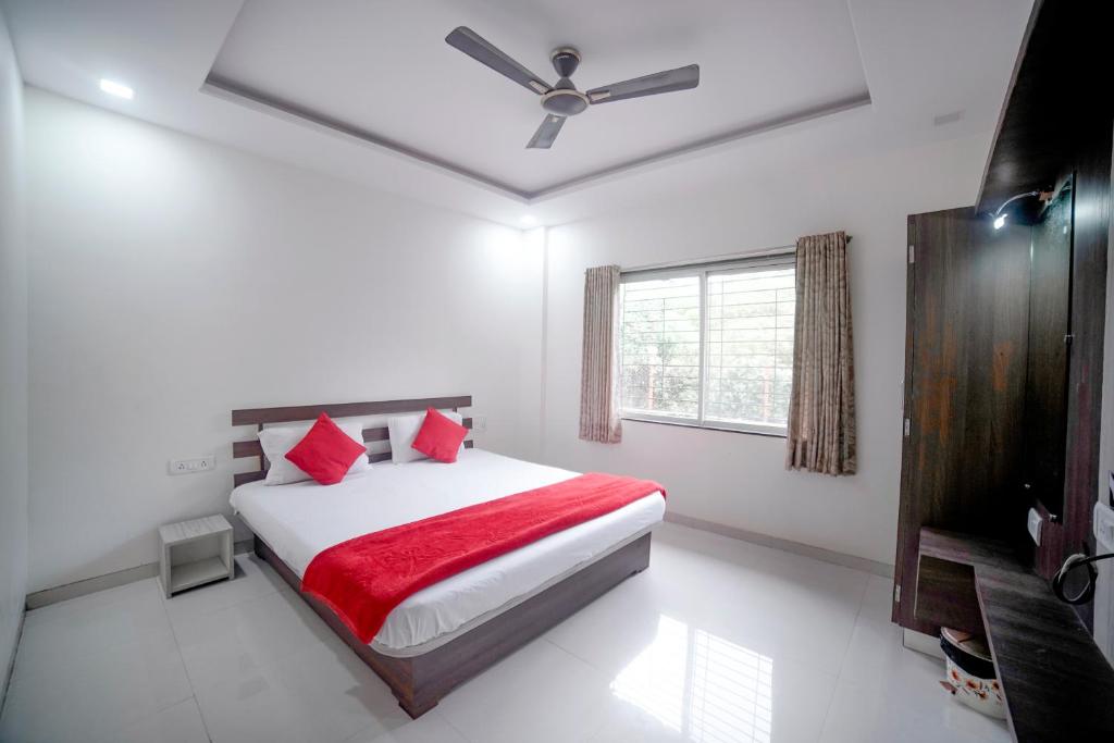 Schlafzimmer mit einem Bett mit roten Kissen und einem Fenster in der Unterkunft Highgarden Villa in Mahabaleshwar