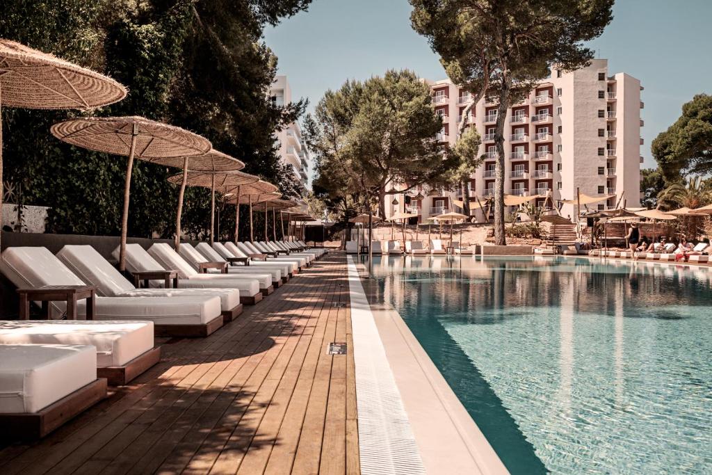 una piscina con tumbonas y sombrillas junto a un edificio en Cooks Club Palma Beach - Adults Only, en Playa de Palma