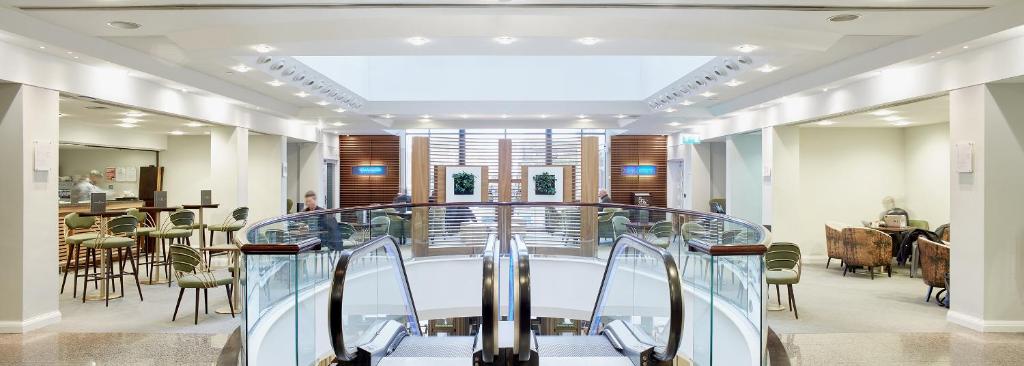 a lobby with a staircase and tables and chairs at Stamford Bridge Hotel London in London