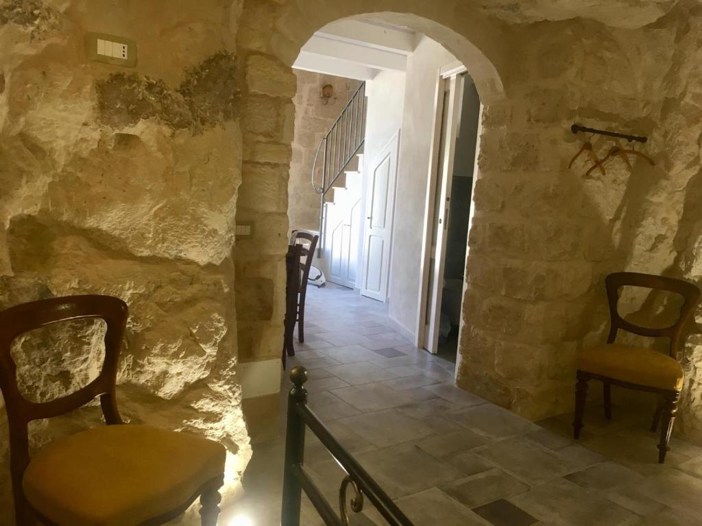 einen Flur mit Stühlen und einer Steinmauer in der Unterkunft La grotta di nonna minicchia n 49 in Scicli