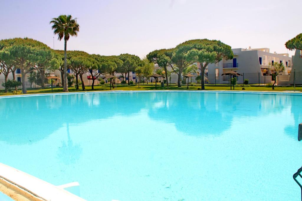 uma grande piscina azul com árvores e edifícios em Apartamento La Barca em Chiclana de la Frontera