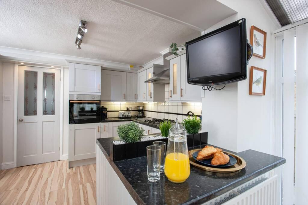 uma cozinha com armários brancos e uma televisão de ecrã plano em Rose Hill Retreat em Low Etherley