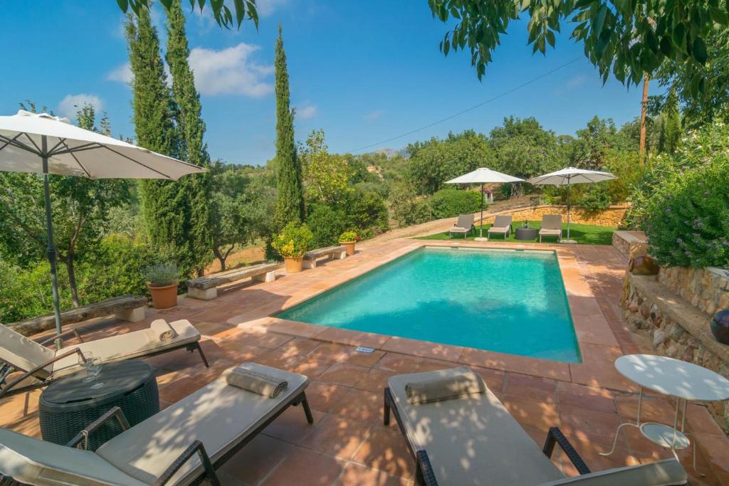 una piscina con sillas y sombrillas en un patio en Es Garroveral 3, en Bunyola