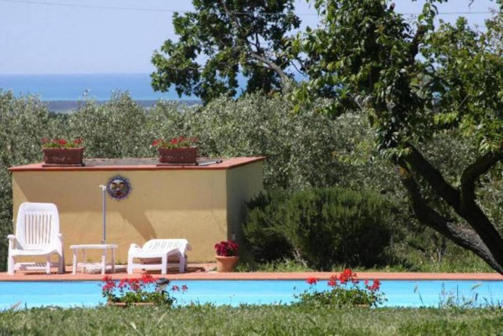 a swimming pool with two chairs and a house at Vigna Lontana in Montescudaio