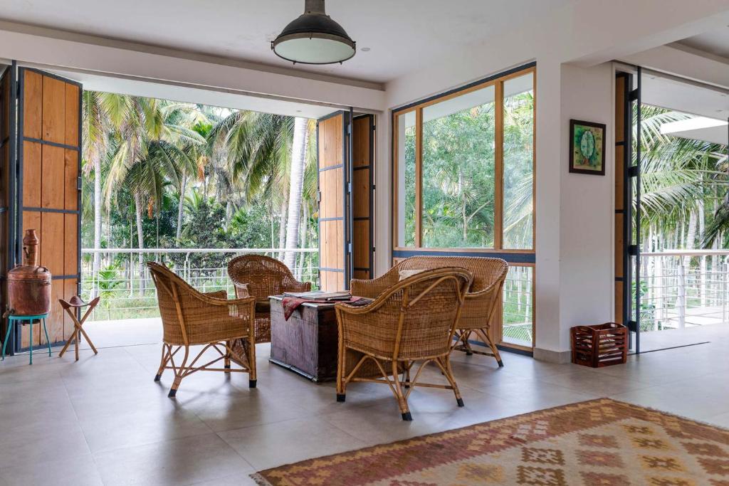 uma sala de estar com uma mesa, cadeiras e janelas em StayVista at Davey's Townhouse with Breakfast & Pet Friendly Home em Mysore