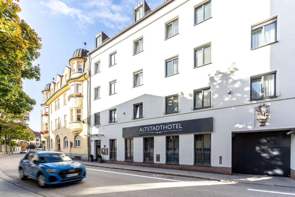 インゴルシュタットにあるアルトシュタットホテルの白い建物を通り抜ける青い車