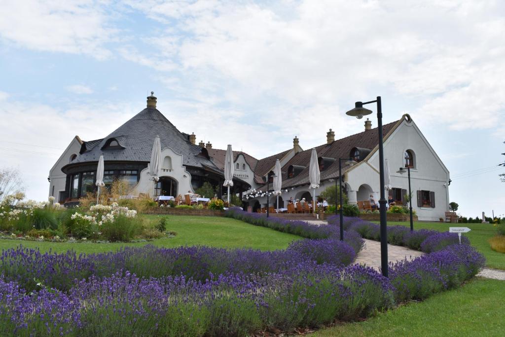 una casa con flores púrpuras delante de ella en Fiastyúk Udvarház, en Csór