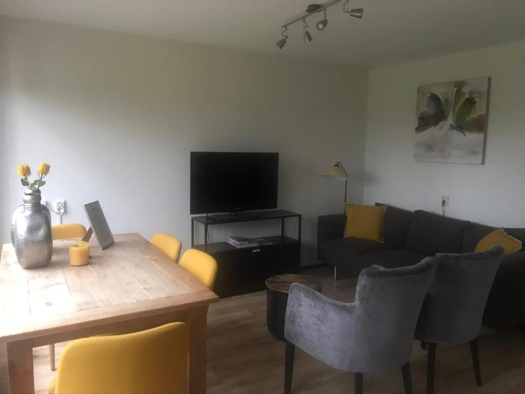 a living room with a table and a couch at Bungalows Hoefbos in Otterlo