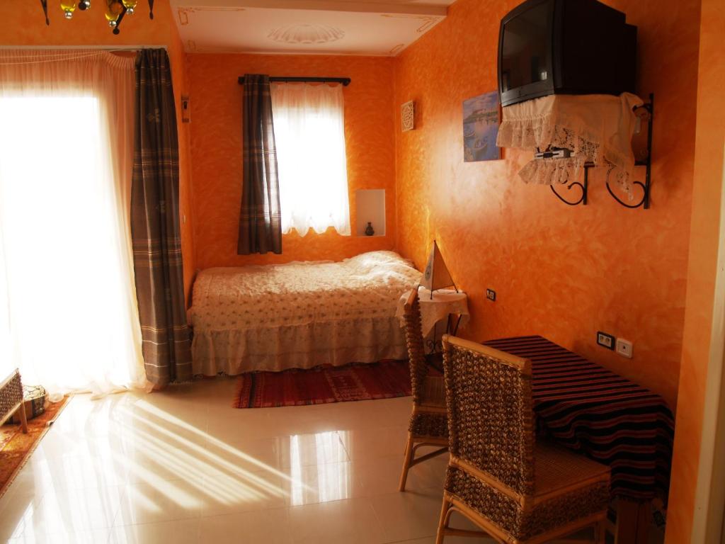1 dormitorio con paredes de color naranja, 1 cama y ventana en Dar El Amen Appartements en Mahdia