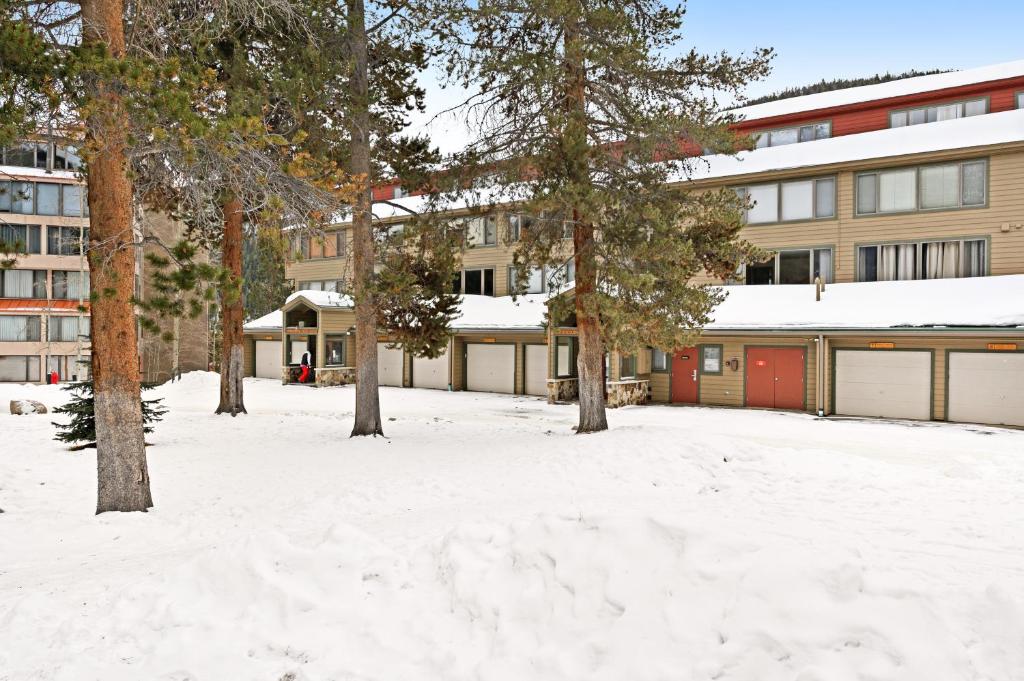 a snow covered yard with trees and a building at Montezuma Condominiums in Keystone