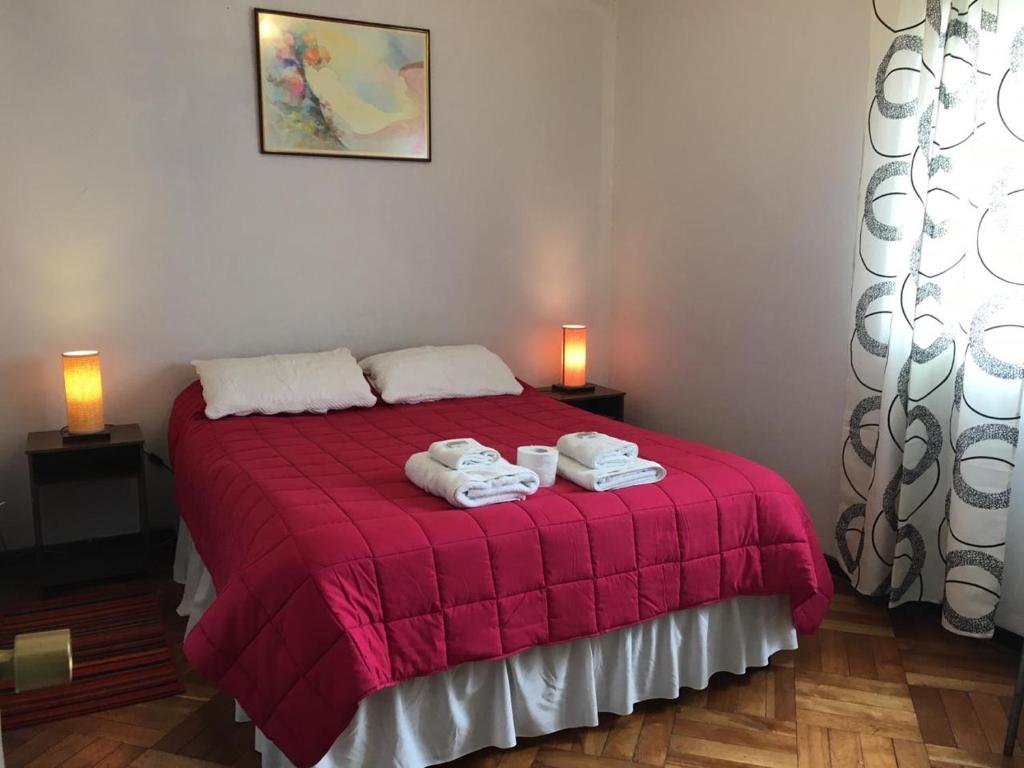 Un dormitorio con una cama roja con toallas. en Viña Colores en Viña del Mar