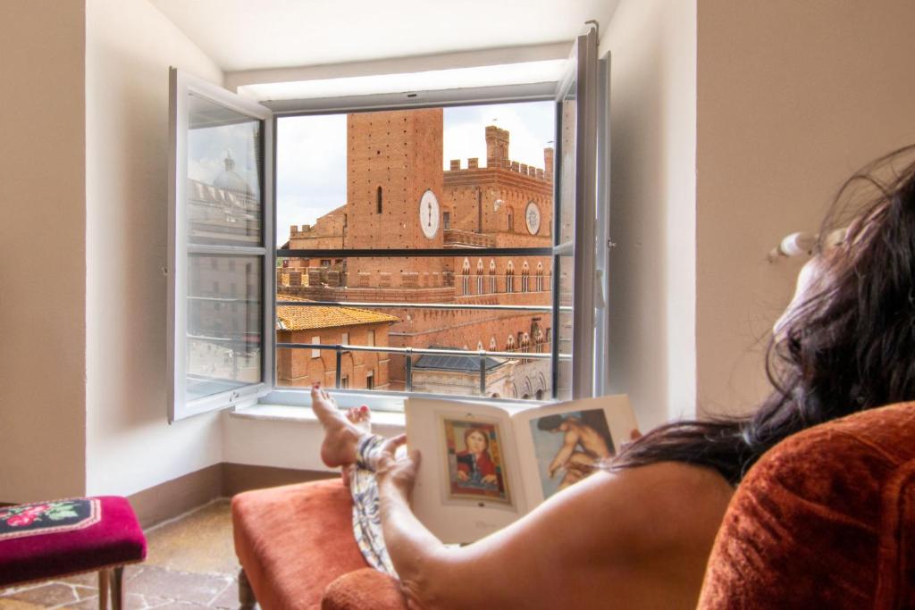a woman sitting in a chair looking out a window at Palazzo Chigi Zondadari in Siena