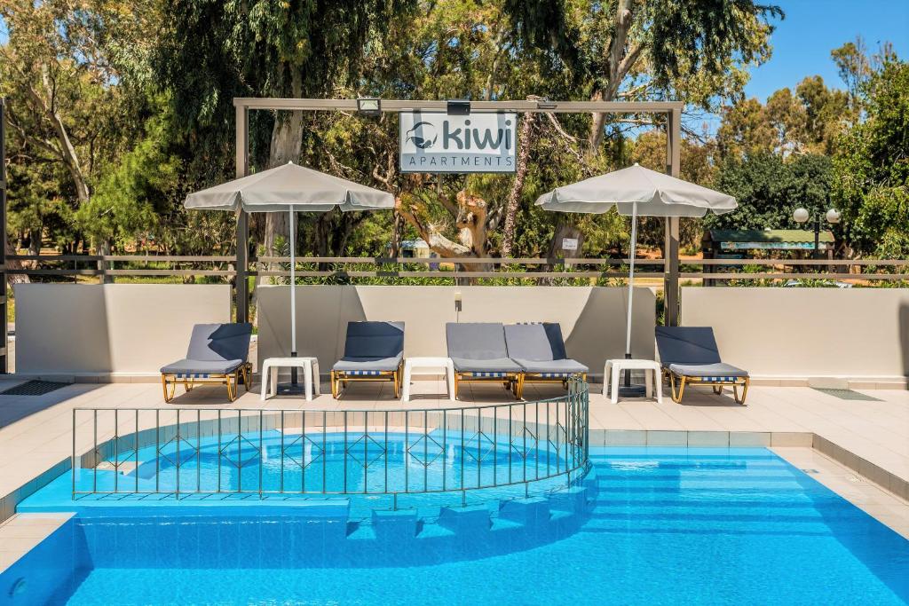 uma piscina num hotel com cadeiras e guarda-sóis em Kiwi Apartments em Kato Daratso