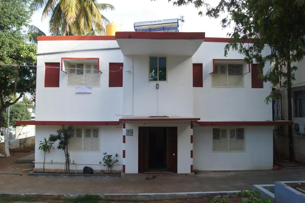 a white house with red windows and a door at Cornerbunker in Mysore