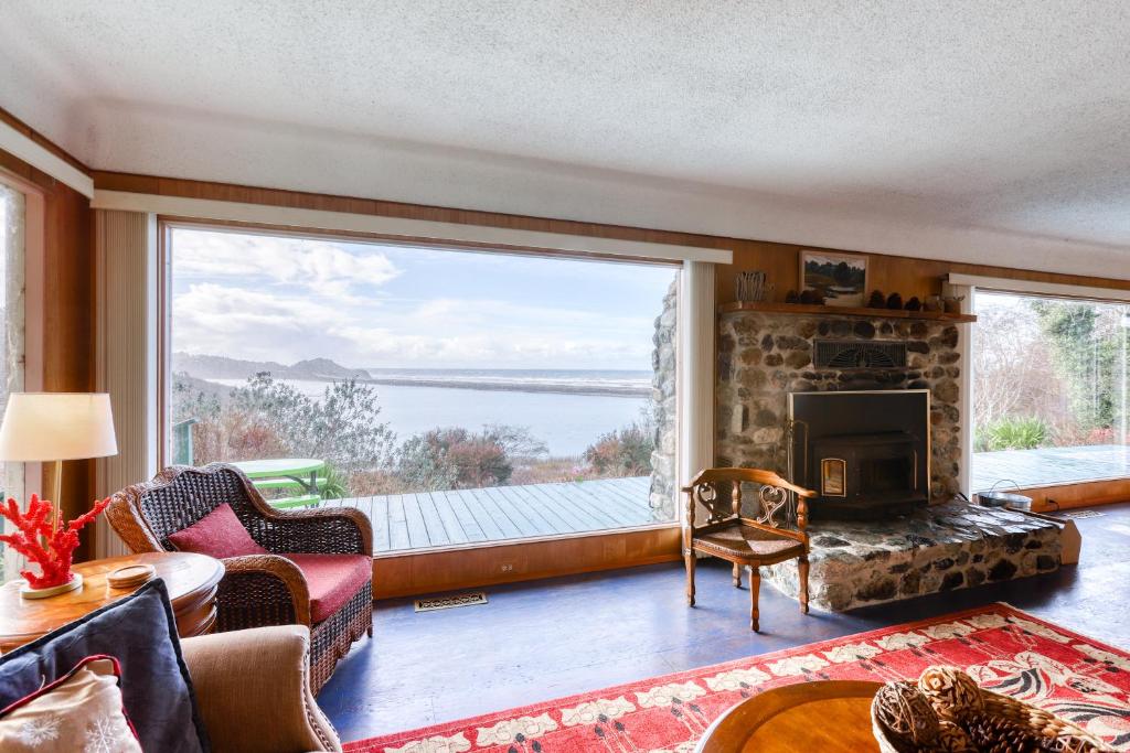 uma sala de estar com lareira e uma grande janela em Freshwater Lagoon Retreat em Orick
