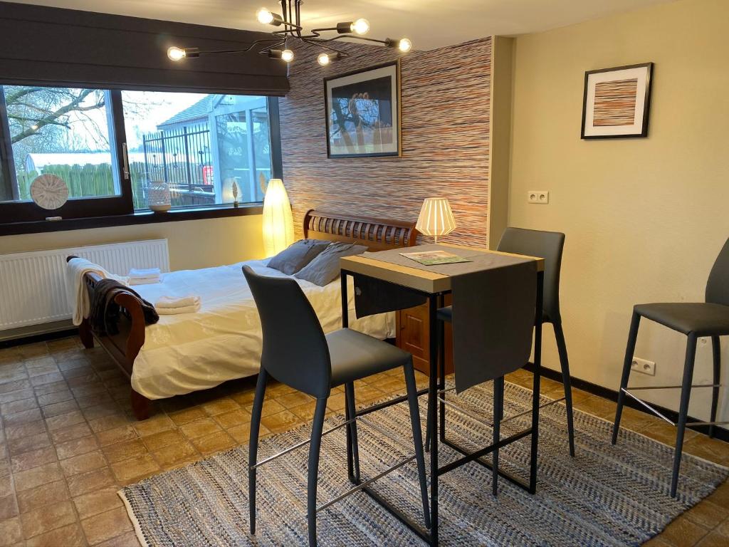a bedroom with a bed and a table and chairs at Studio Rue de Pommard in Francorchamps
