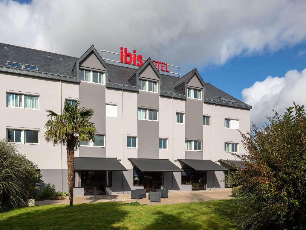 - un grand bâtiment blanc avec un grand panneau dans l'établissement ibis Quimperle, à Quimperlé