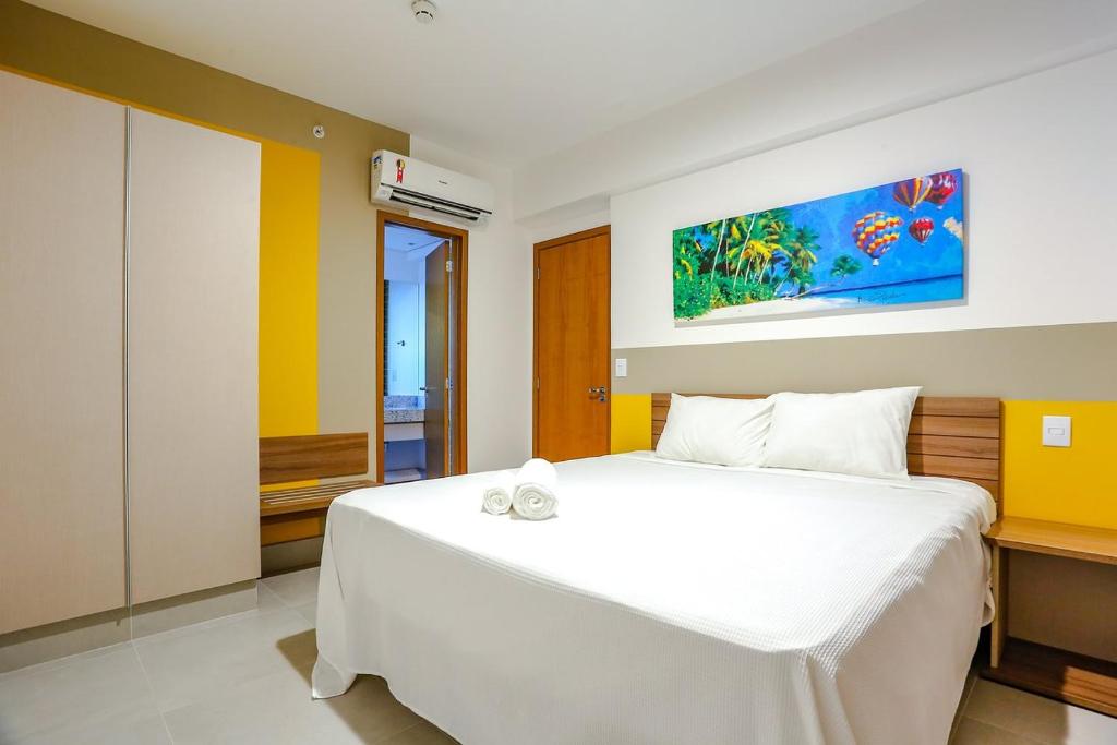 a bedroom with a white bed and a painting on the wall at Apartamento em Resort de Olímpia - Direto com Dono Apto 1201 in Olímpia