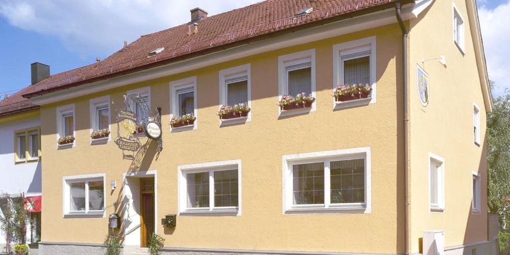 a yellow building with a clock in front of it at Hotel u. Restaurant Goldener Greifen in Donauwörth