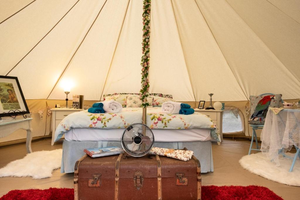 a bedroom with a bed with a fan and a suitcase at The Primrose at Paradise Valley Glamping in Kerikeri