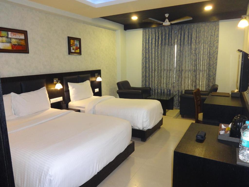 a hotel room with two beds and a desk at Pride Ananya Resorts in Puri