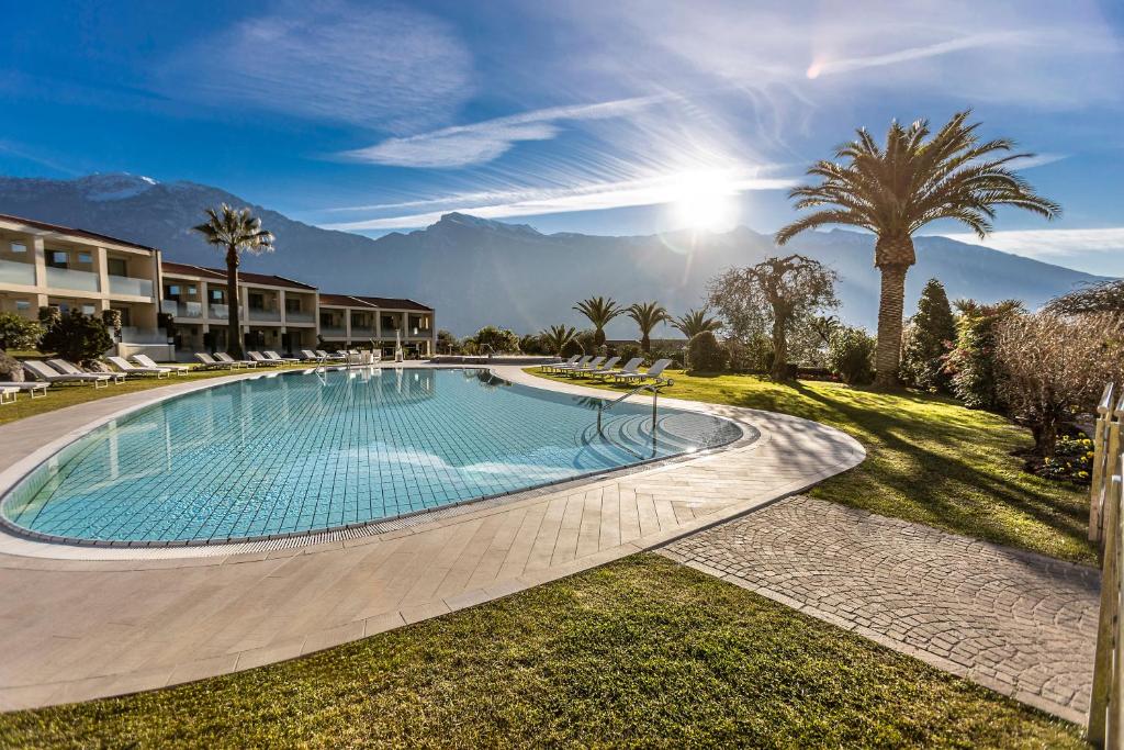 a swimming pool in a resort with palm trees and mountains at Park Hotel Imperial in Limone sul Garda
