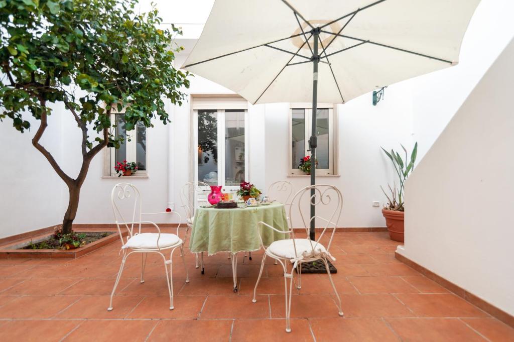un patio con mesa, sillas y sombrilla en La dimora del Cavaliere di Squinzano, en Squinzano