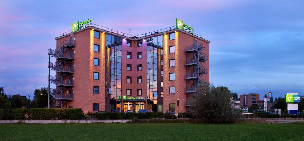 un alto edificio di mattoni con luci sopra di Holiday Inn Express Reggio Emilia, an IHG Hotel a Reggio Emilia
