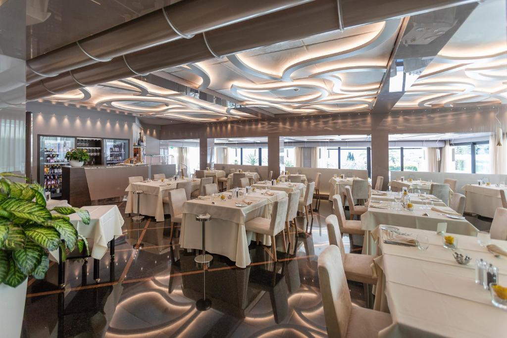 a dining room with white tables and chairs at Park Hotel Imperial in Limone sul Garda