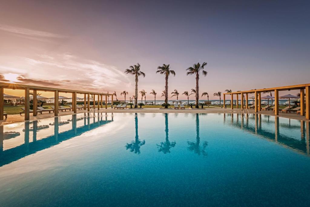 una gran piscina con palmeras en el fondo en Mitsis Selection Alila en Faliraki