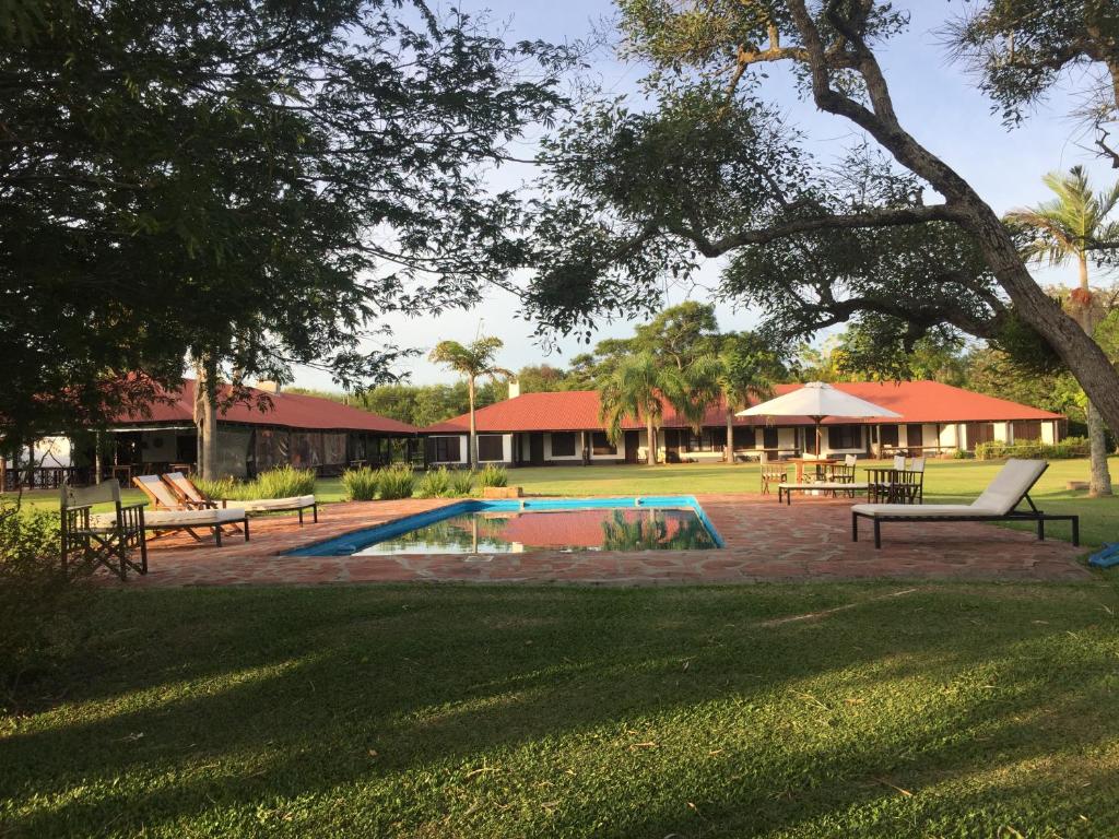 un parc avec une piscine, des bancs et un bâtiment dans l'établissement Aguapé Lodge, à Colonia Carlos Pellegrini