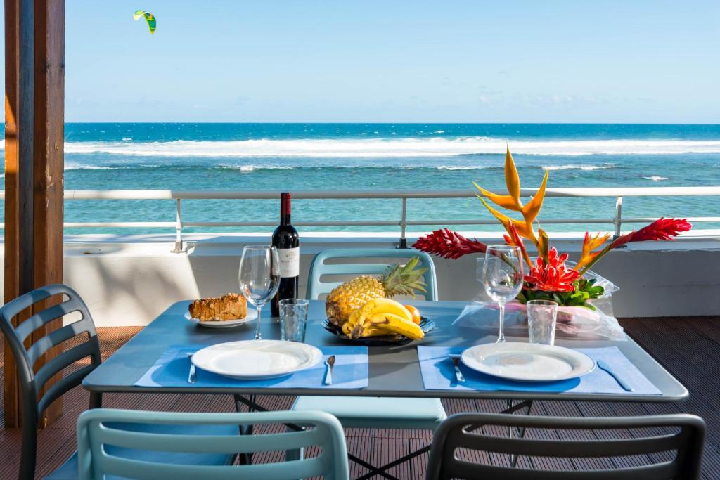 - une table avec deux assiettes de nourriture et une vue sur l'océan dans l'établissement T2B Lagon Austral "parenthèse australe", à Saint-Pierre