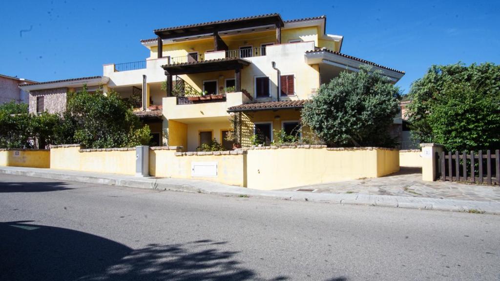 a yellow building with a fence on the side of a street at Il Giardino dei Limoni Apartment in Santa Teresa Gallura
