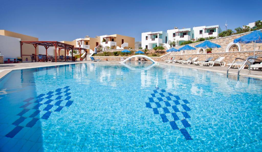 una grande piscina blu con sedie e ombrelloni di Golden Sun Apartments ad Arkása