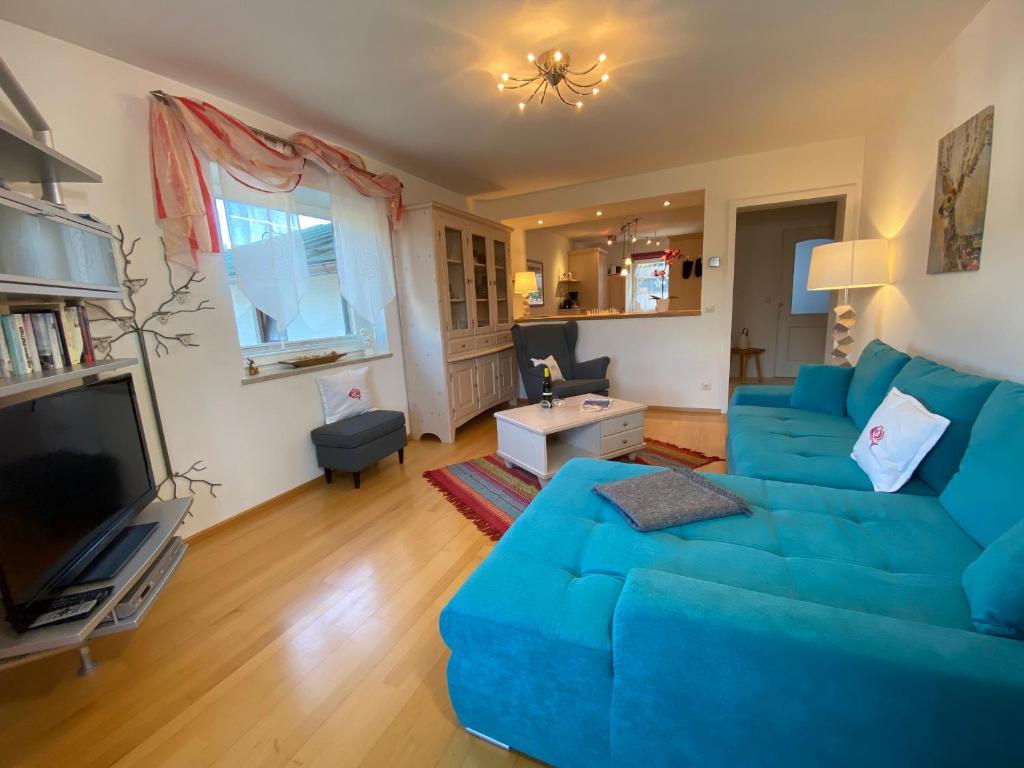 a living room with a blue couch and a television at FeWo Waldkauz in Berchtesgaden