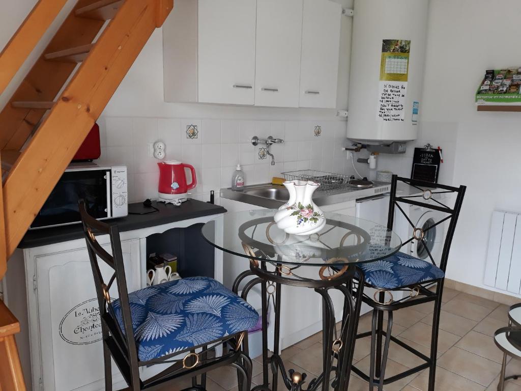 a small kitchen with a glass table and two chairs at Chambres d'Hotes Elvire et Laurent Barbey in Sainte-Marie-du-Mont