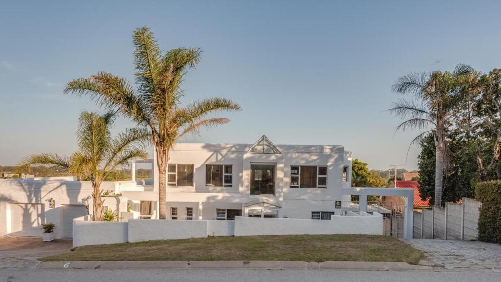 uma casa branca com palmeiras em frente em The White House em Port Elizabeth