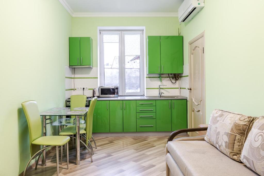 リヴィウにあるChaikovskoho apartmentのキッチン(緑のキャビネット、テーブル、ソファ付)