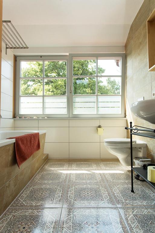 a bathroom with a tub and a sink and two windows at Hügelhus in Kloster