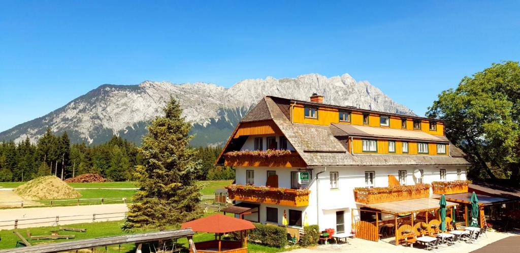 uma casa grande com uma montanha ao fundo em Hotel Pension Pürcherhof em Gröbming