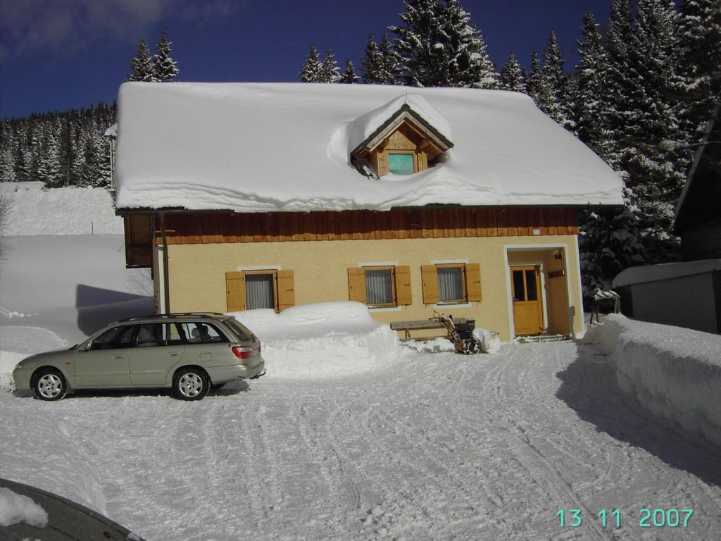 un coche aparcado frente a una casa cubierta de nieve en Ferienwohnung A 55 m2, en Lachtal