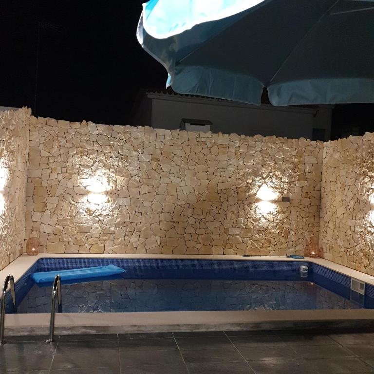 a swimming pool with lights on a stone wall at Bella's House 4 com Piscina in Évora