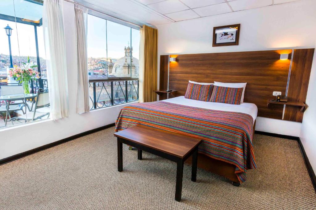 a hotel room with a bed with a table and a window at Conde de Lemos Hotel in Puno
