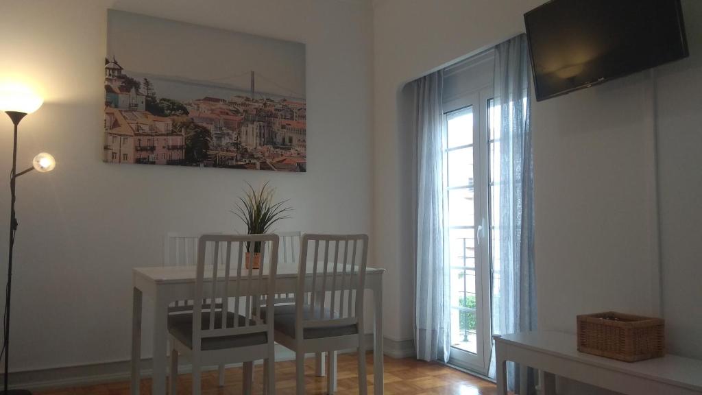 ein Esszimmer mit einem Tisch, Stühlen und einem Fenster in der Unterkunft Alvalade Inn in Lissabon