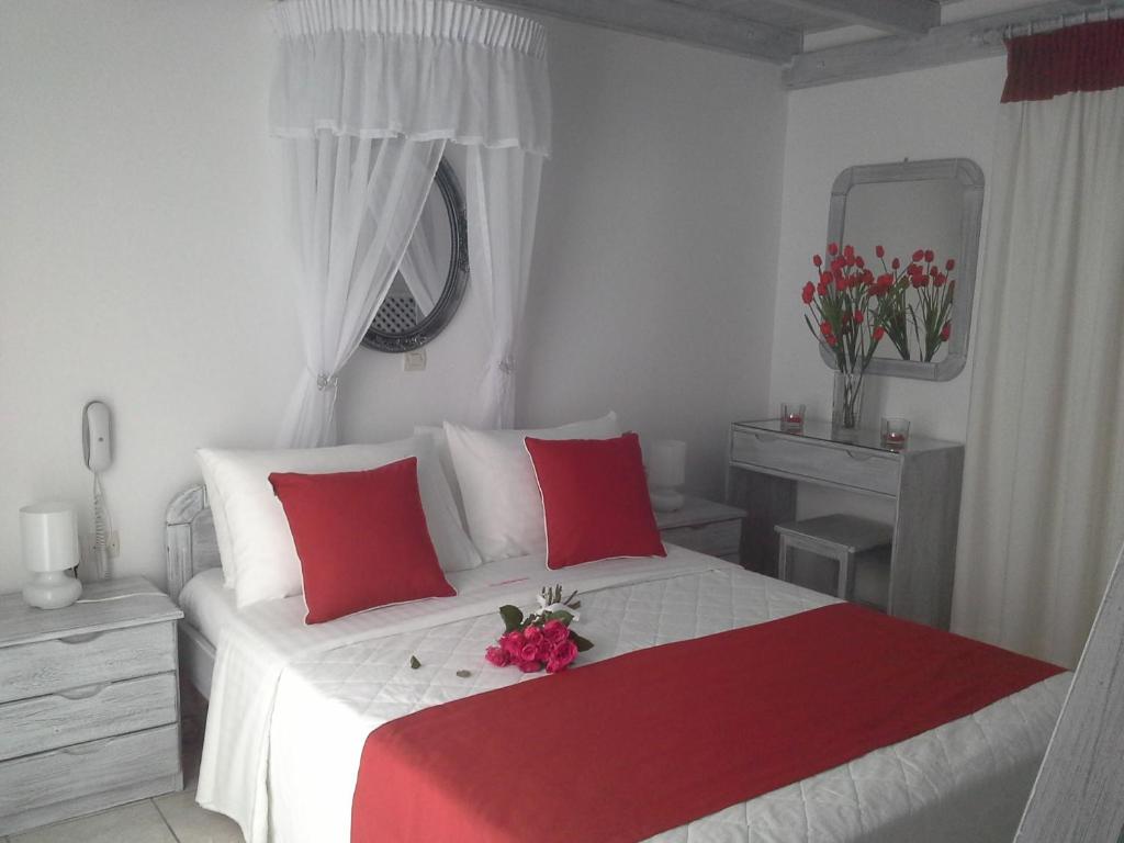 a bedroom with a white bed with red pillows at Kiklamino Sunset Studios in Oia
