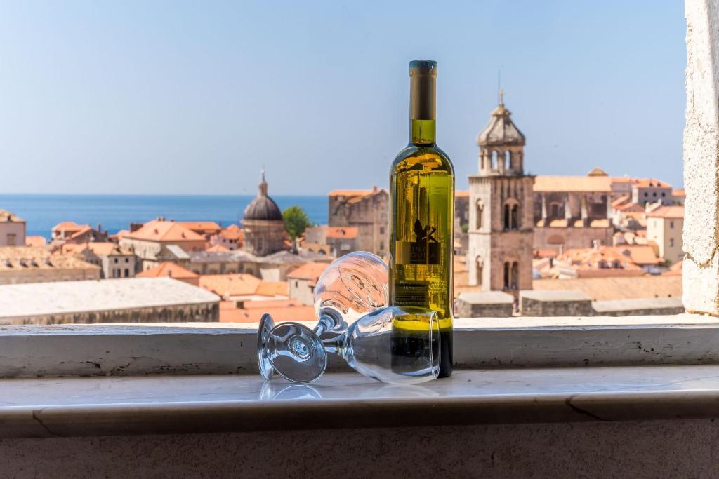 una bottiglia di vino e bicchieri seduti su un davanzale della finestra di Apartments Casa Vanna a Dubrovnik