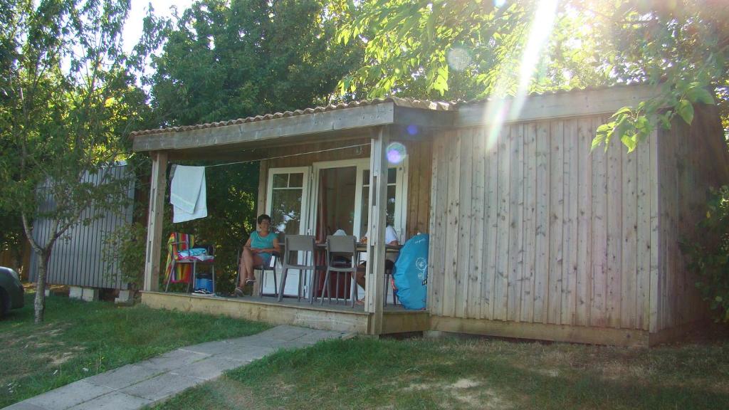 a woman is sitting in a small shed at CAMPING LES GRAVES in Saint-Pierre-Lafeuille