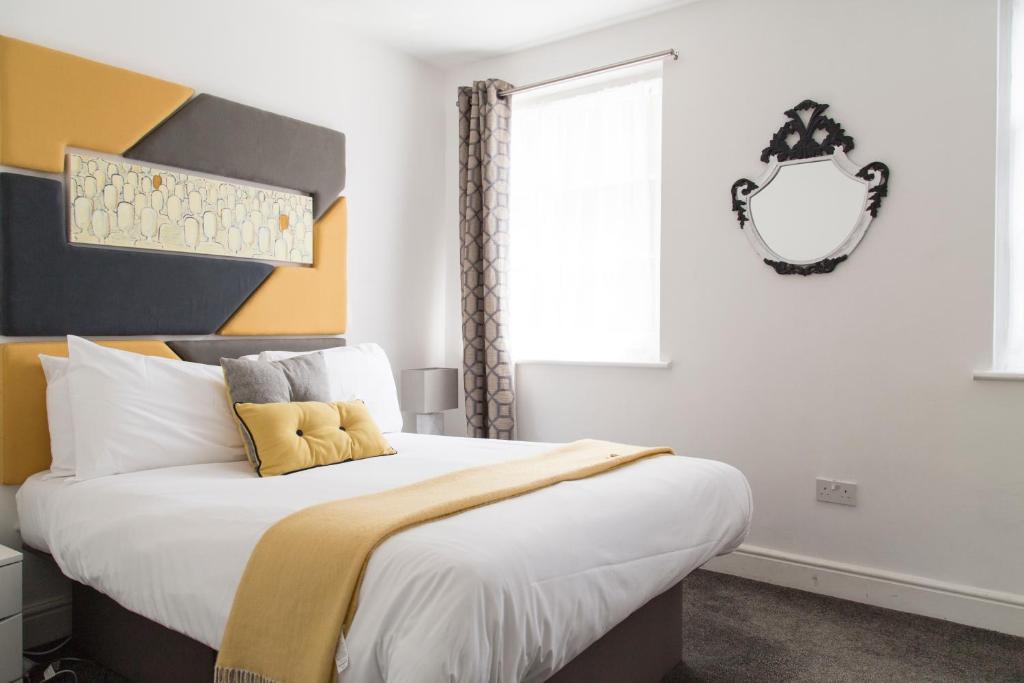 sypialnia z dużym łóżkiem z żółtym zagłówkiem w obiekcie Cambridge City Studios by Paymán Club w Cambridge