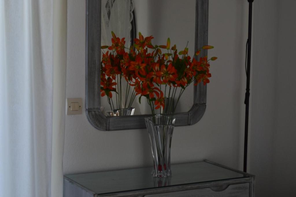 a vase with flowers on a table in front of a mirror at Kiklamino Sunset Studios in Oia